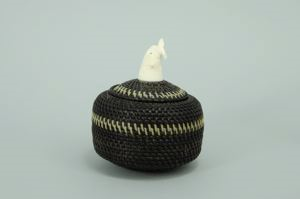 Image of baleen basket, black and white with finial carved as otter with fish in mouth